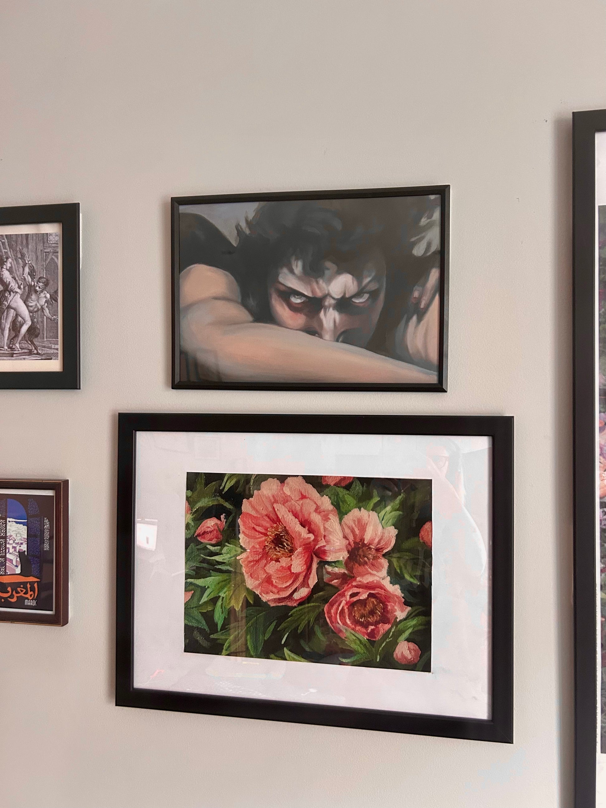 Wall with framed artwork including a floral painting and a black and white portrait.